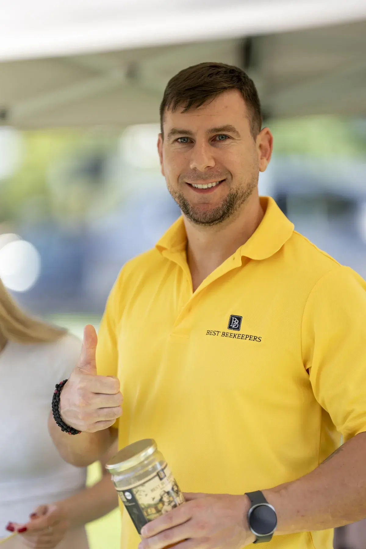 Oleh Haiduk at UAFest 2026 — Honey vendor in a yellow polo gives a thumbs up holding a jar (photo: Tim Skinner)