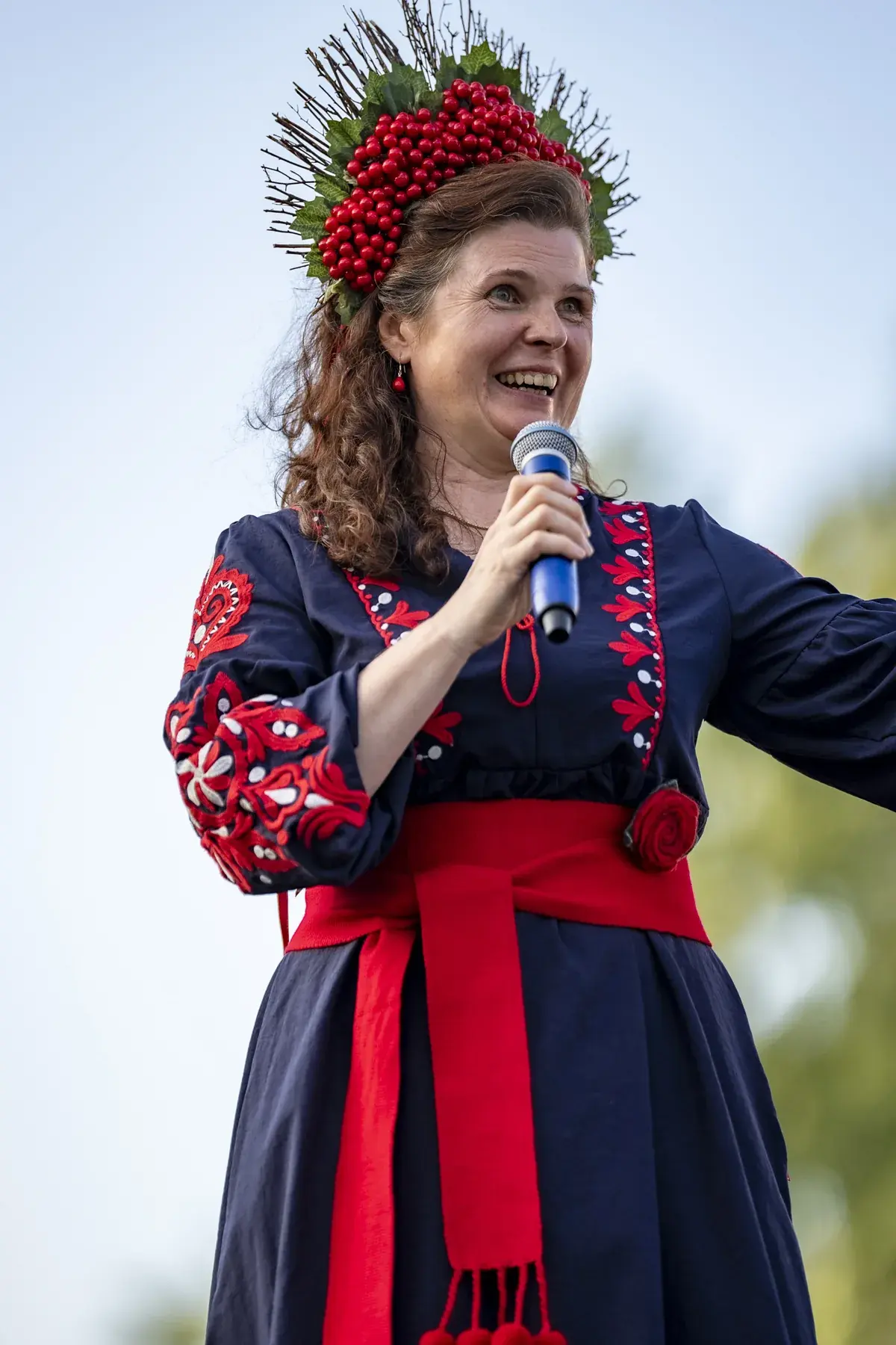 Oksana Pikush at UAFest 2026 — Smiling host in a viburnum crown and navy embroidered dress with microphone (photo: Tim Skinner)
