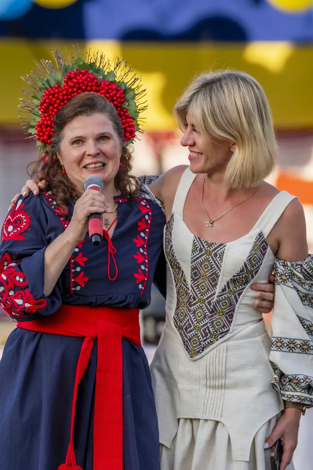 Svitlana Marchuk at UAFest 2026 — Woman in viburnum wreath speaks, embracing a blonde performer (photo: Tim Skinner)