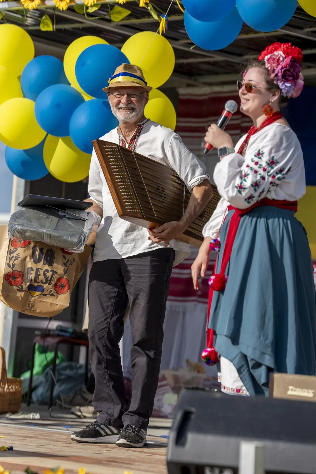 Olga Ostafiichuk at UAFest 2026 — Host presents a UA Fest gift bag to the cymbaly player on stage (photo: Tim Skinner)
