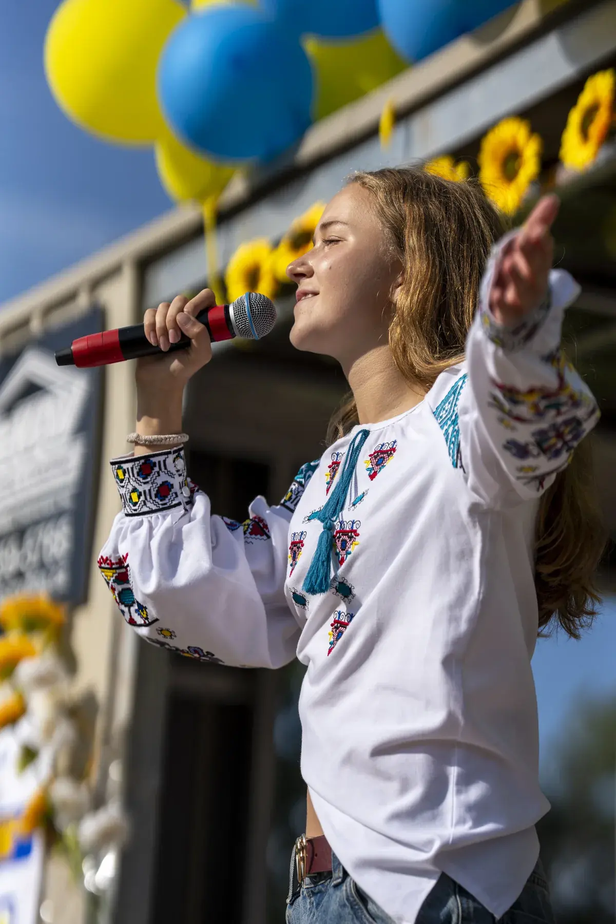 Marta Stepanenko at UAFest 2026 — Teen singer with arm outstretched sings among yellow-blue balloons (photo: Tim Skinner)