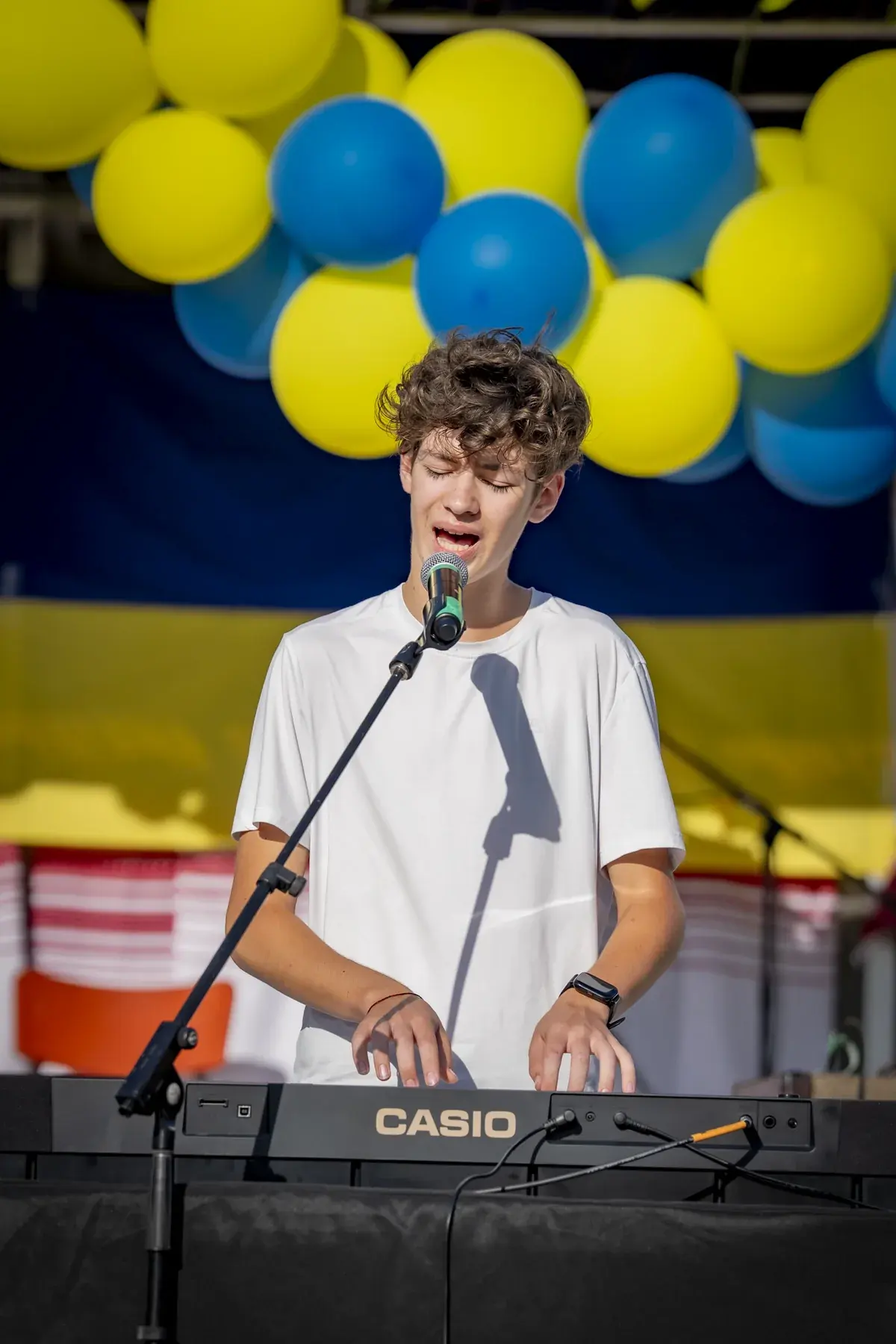 Ivan Horobets at UAFest 2026 — Teenage keyboardist singing on stage under blue and yellow balloons (photo: Tim Skinner)