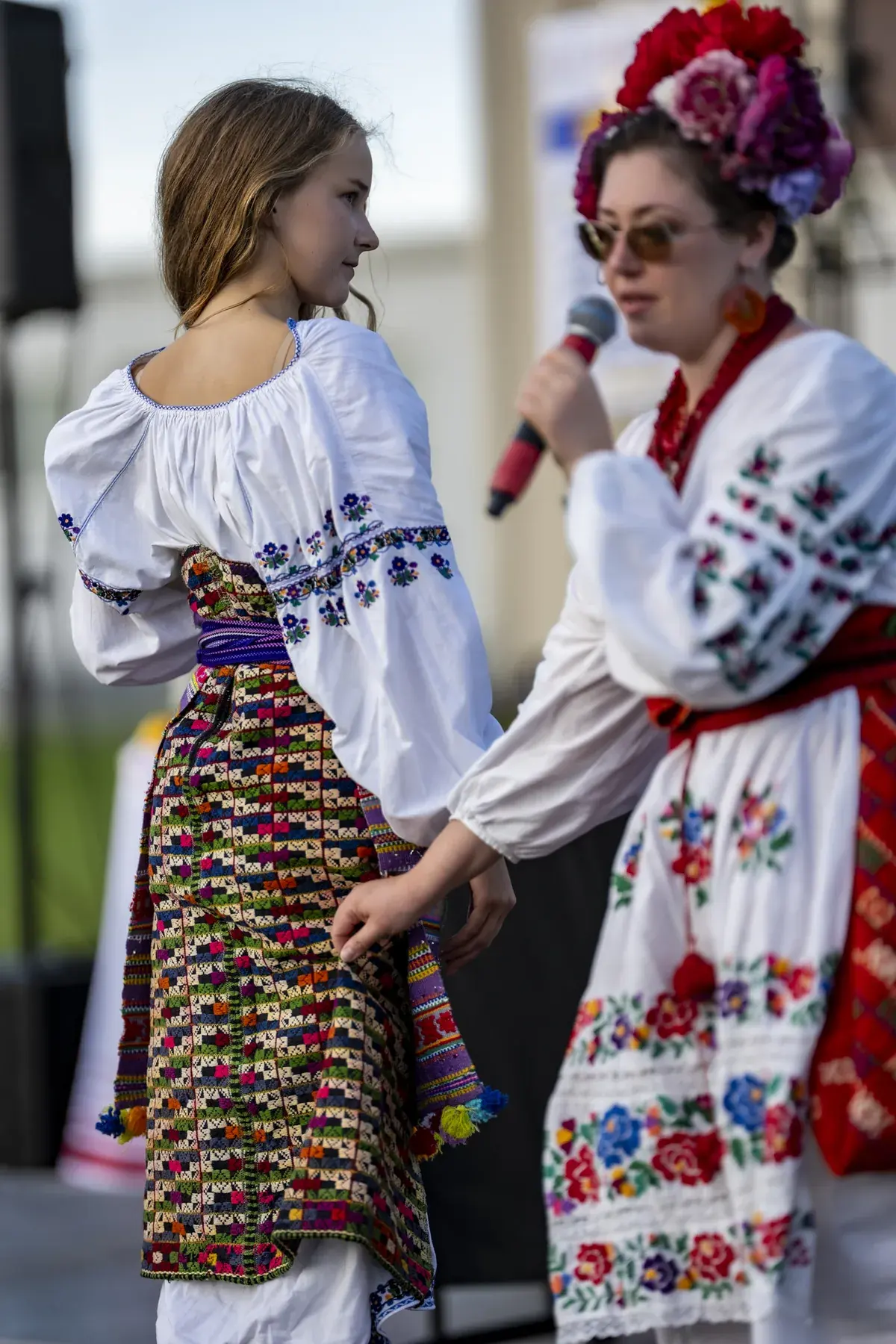 Marta Stepanenko at UAFest 2026 — Host with a microphone presents a girl's traditional costume, back view (photo: Tim Skinner)