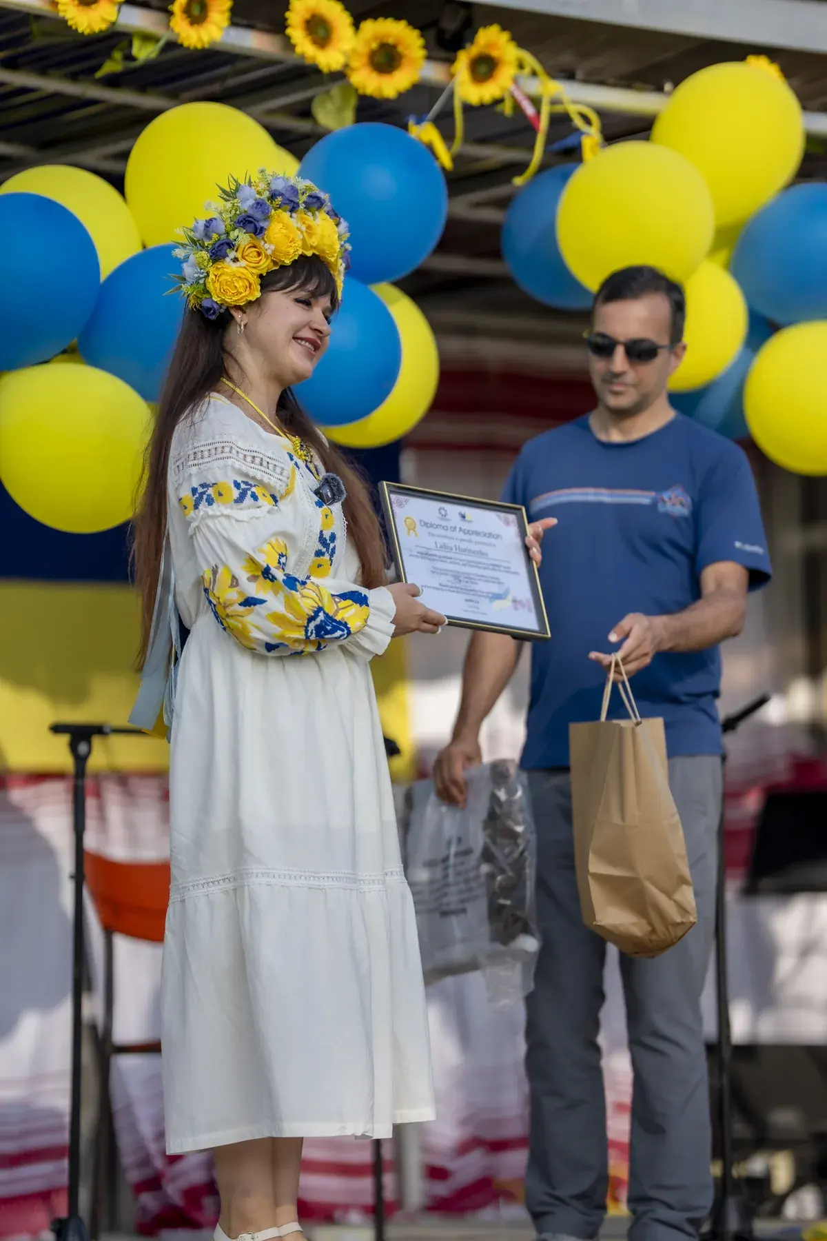 Lidiia Hurinenko at UAFest 2026 — Woman in a flower crown and vyshyvanka presents a certificate on stage (photo: Tim Skinner)