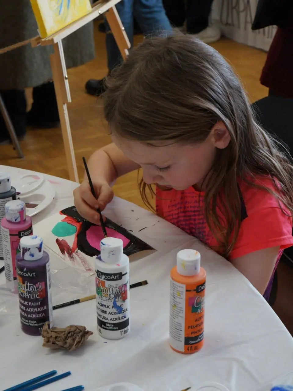 A child concentrating while painting with acrylics at an art workshop table