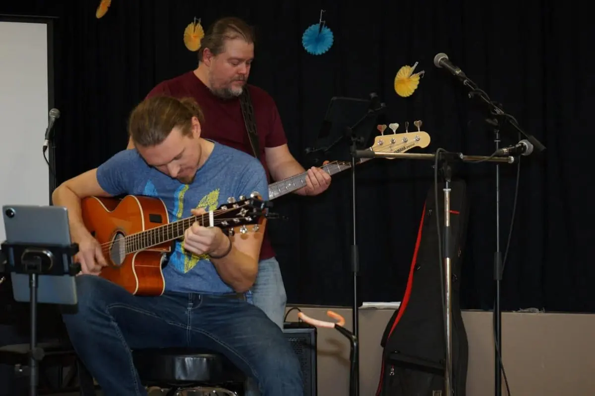 Two musicians performing together on stage at UAFest, one playing an acoustic guitar and the other a bass guitar
