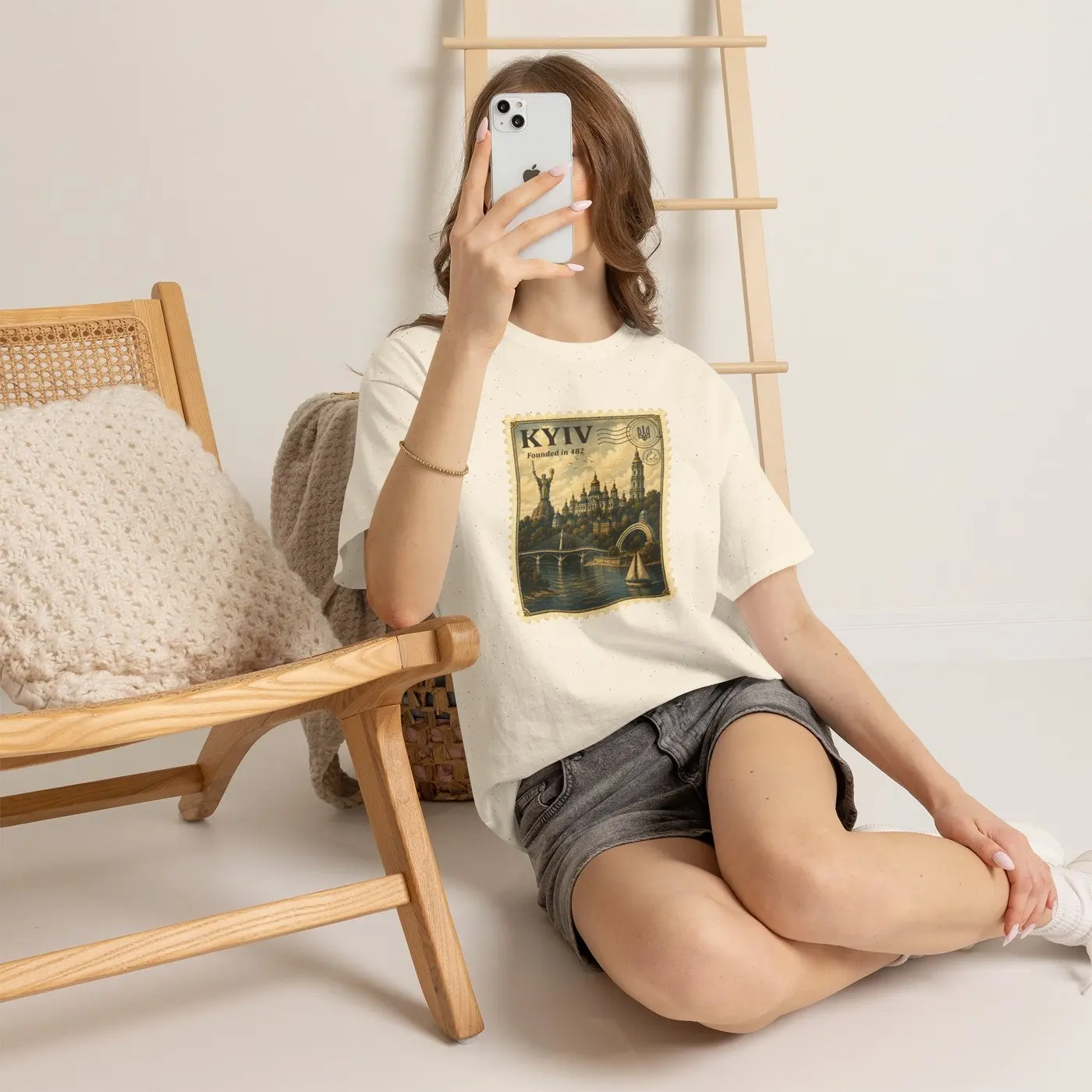 A woman in the Kyiv T-shirt sitting on the floor beside a wooden chair