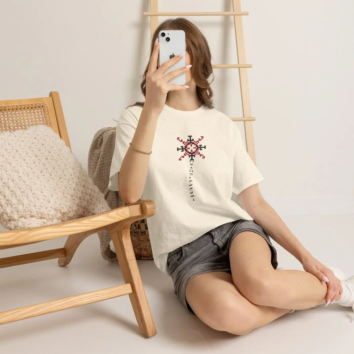 A woman in the T-shirt sitting on the floor beside a wooden chair, the ornament in full view