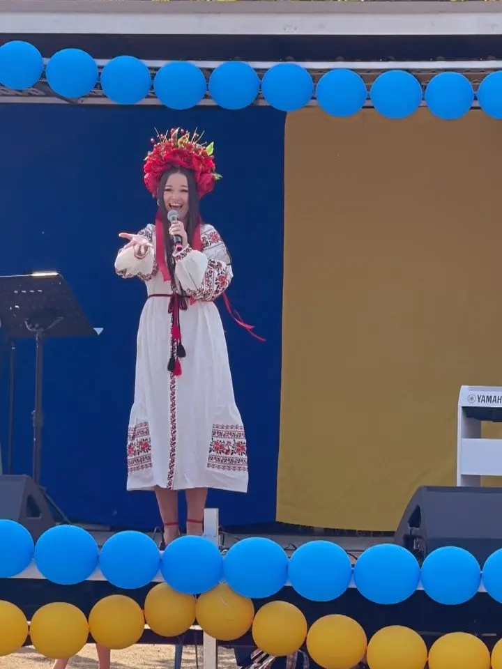 A singer in a white embroidered vyshyvanka and red floral crown performing on the UAFest stage