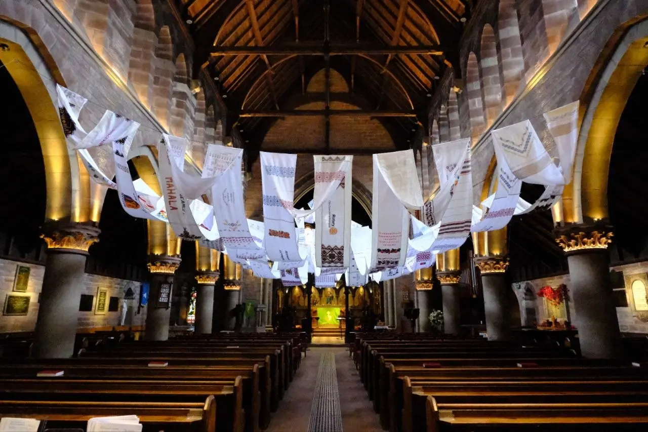 A European-record embroidered rushnyk hanging across the ceiling of a church, dozens of panels from communities across Europe