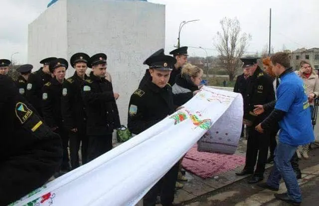 Naval cadets and volunteers unrolling the original rushnyk at a monument in Kherson, 2014