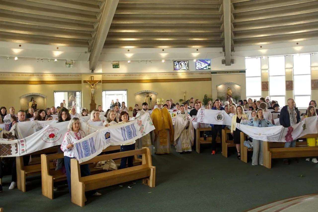 A church full of people holding the rushnyk along the pews during a service