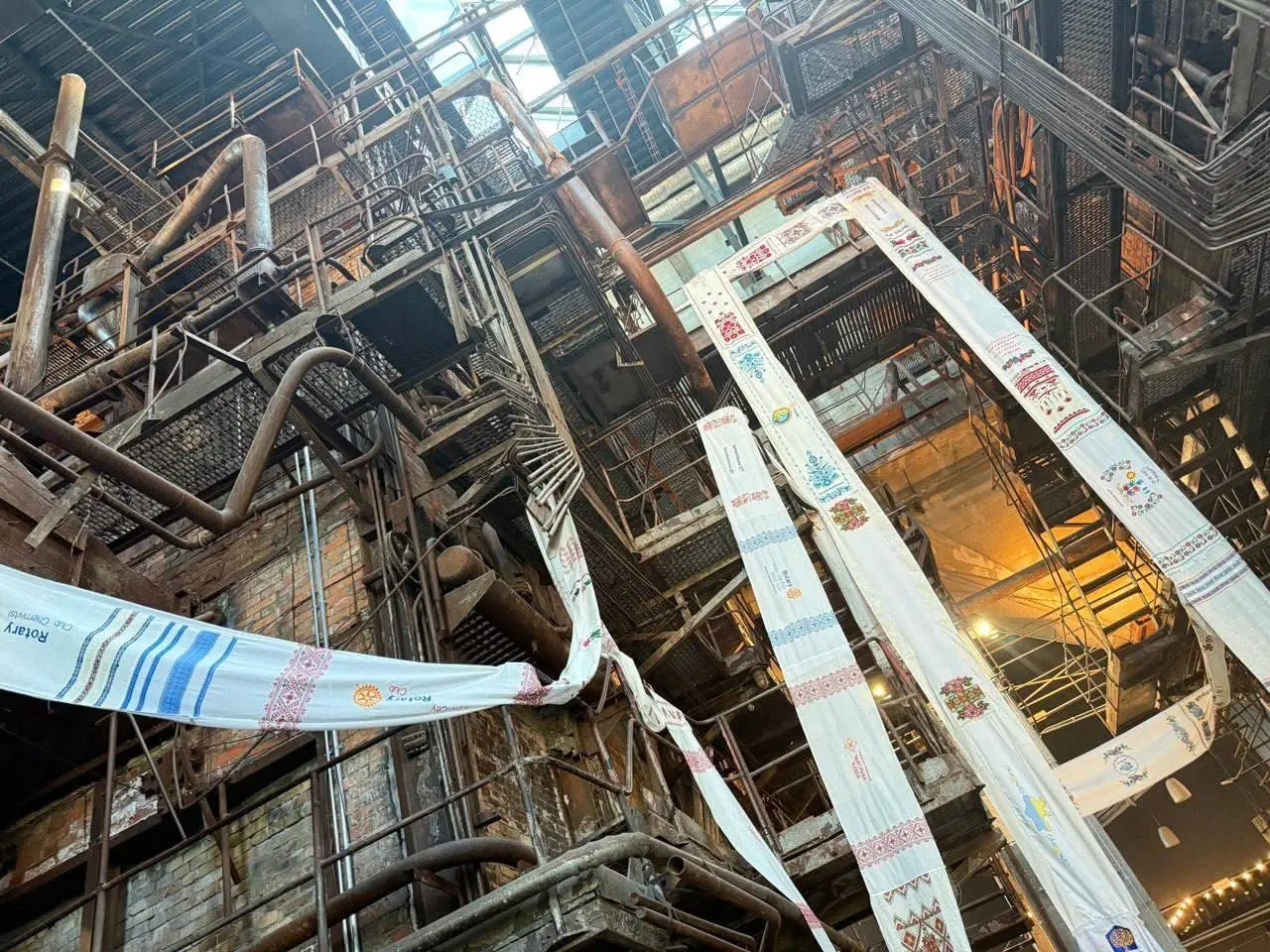 The rushnyk unfurled through the steel galleries of an industrial hall
