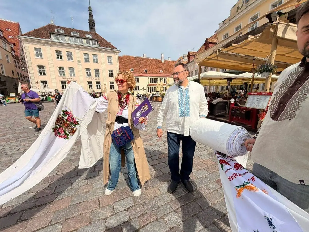 Community members in vyshyvankas carrying the rushnyk across an old-town market square