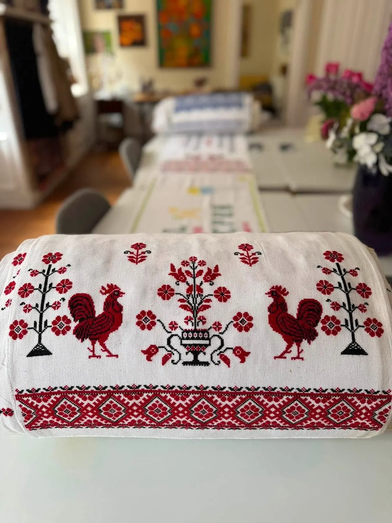 Close view of a panel embroidered with two red roosters and a tree of life
