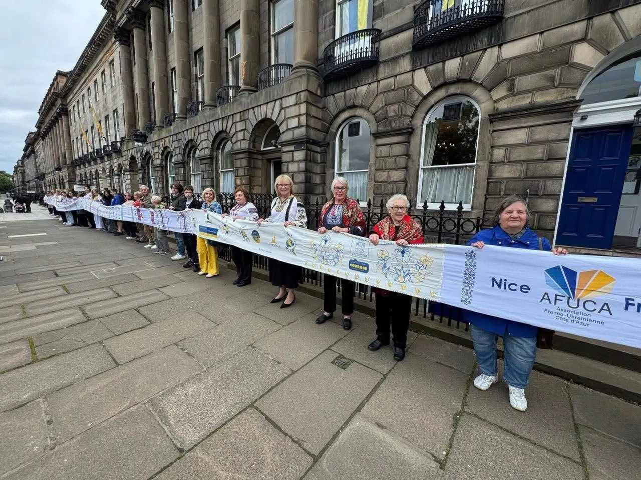 People lining a city street, holding the rushnyk along the railings