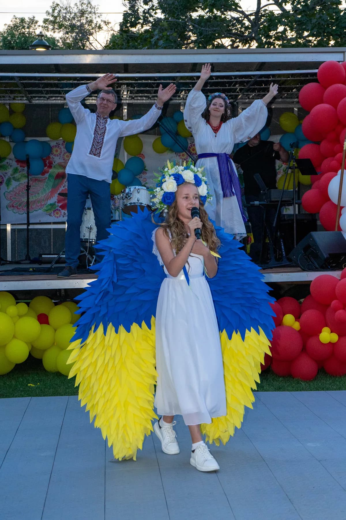 Marta singing in her blue-and-yellow wings as the band on the UAFest 2024 stage raises their hands behind her