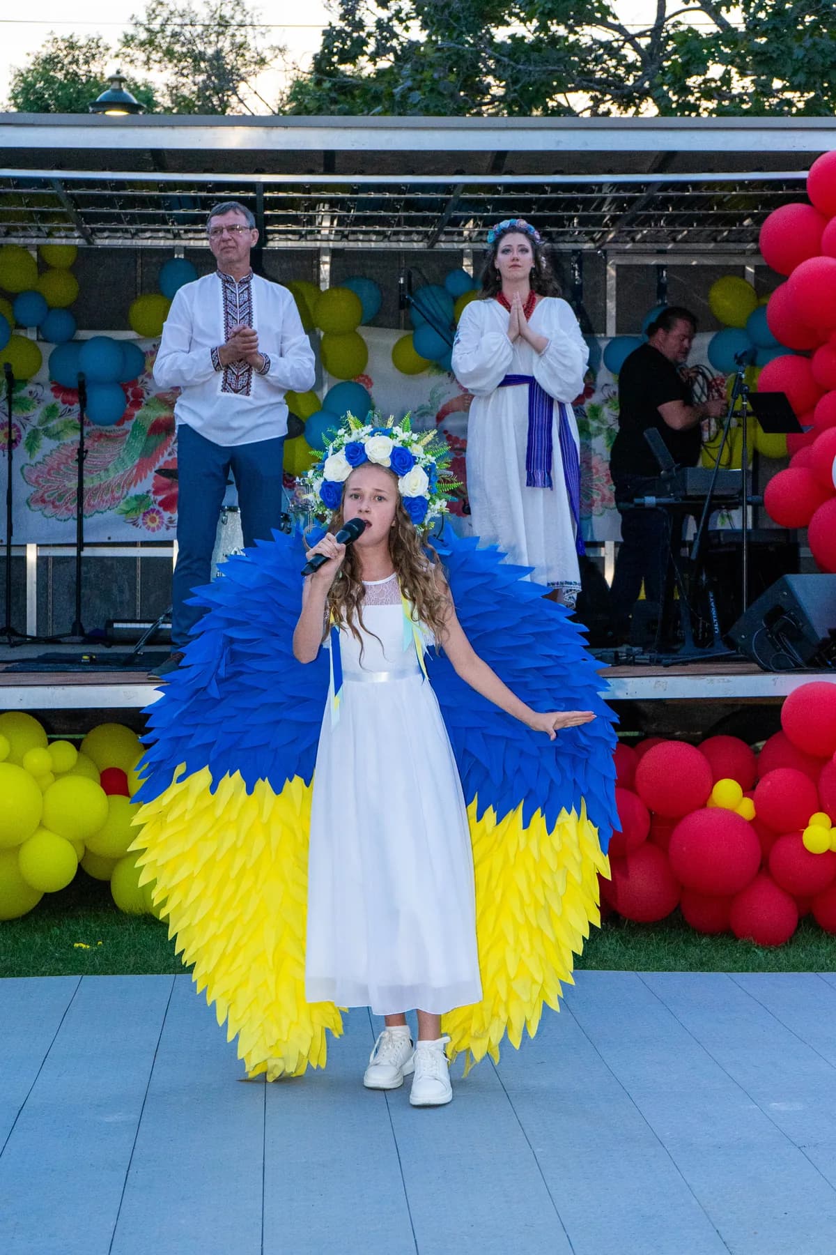 Marta Stepanenko on the UAFest 2024 stage in a white dress with large blue-and-yellow wings, framed by balloon columns