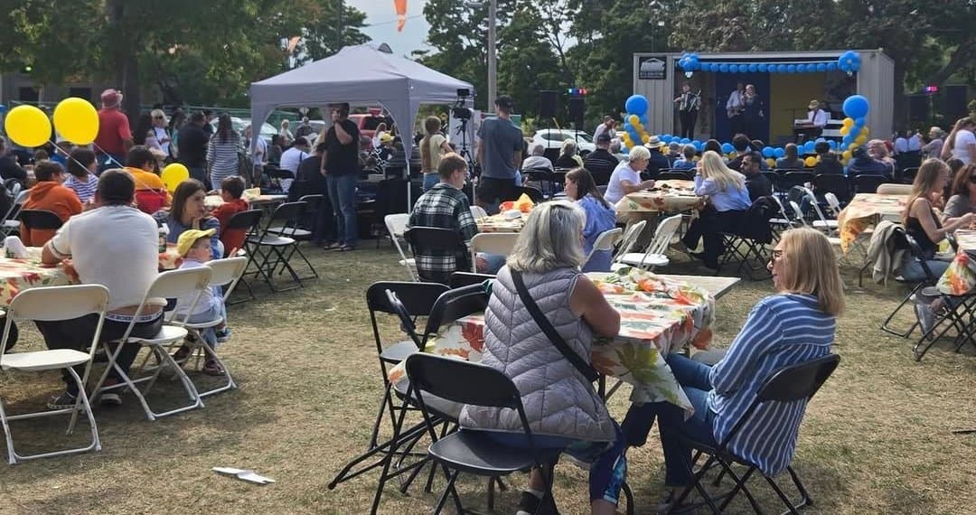 Festival guests seated at outdoor picnic tables on the UAFest grounds between performances.