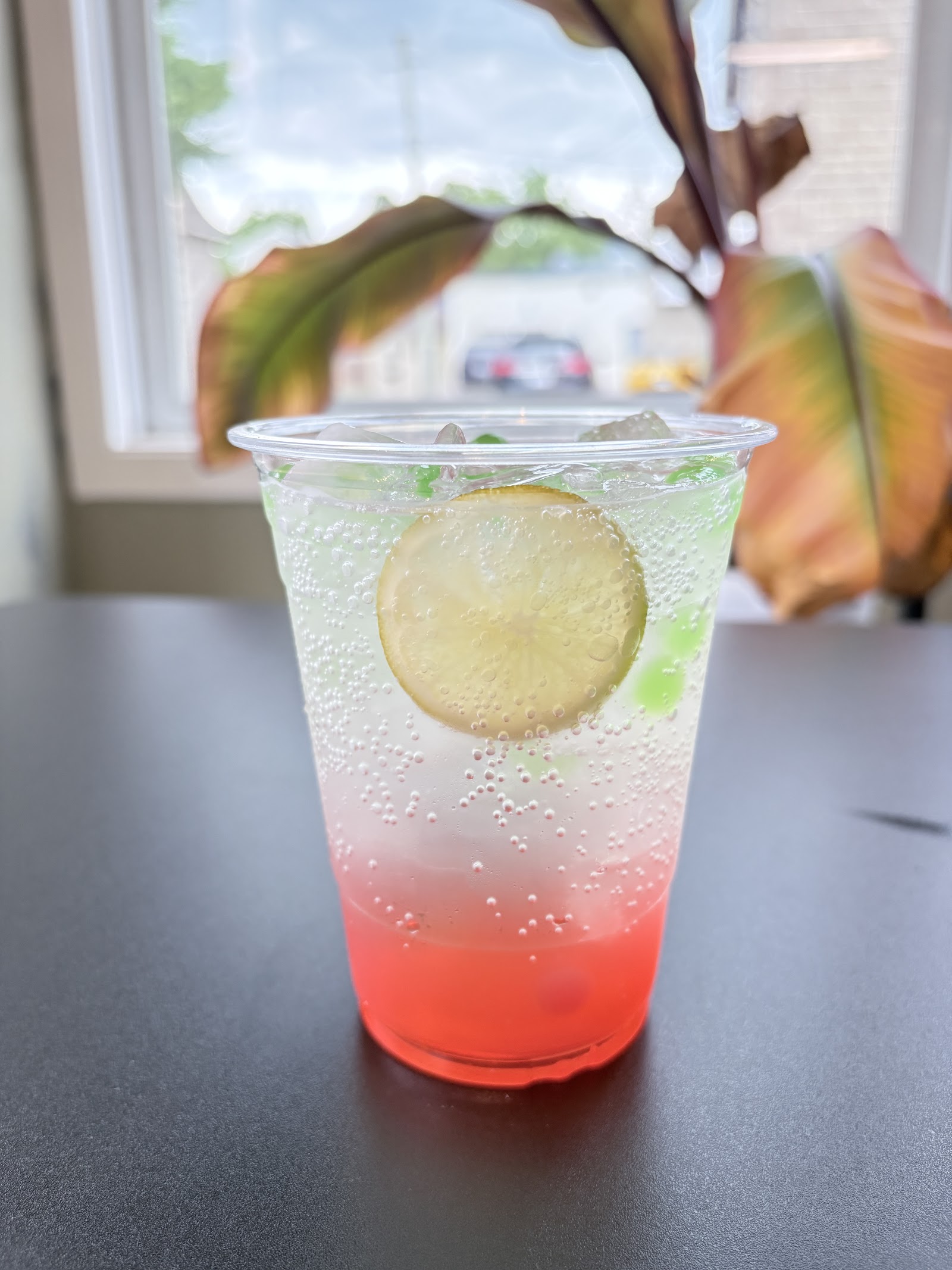 A layered iced drink with a lime wheel on the café table by the window