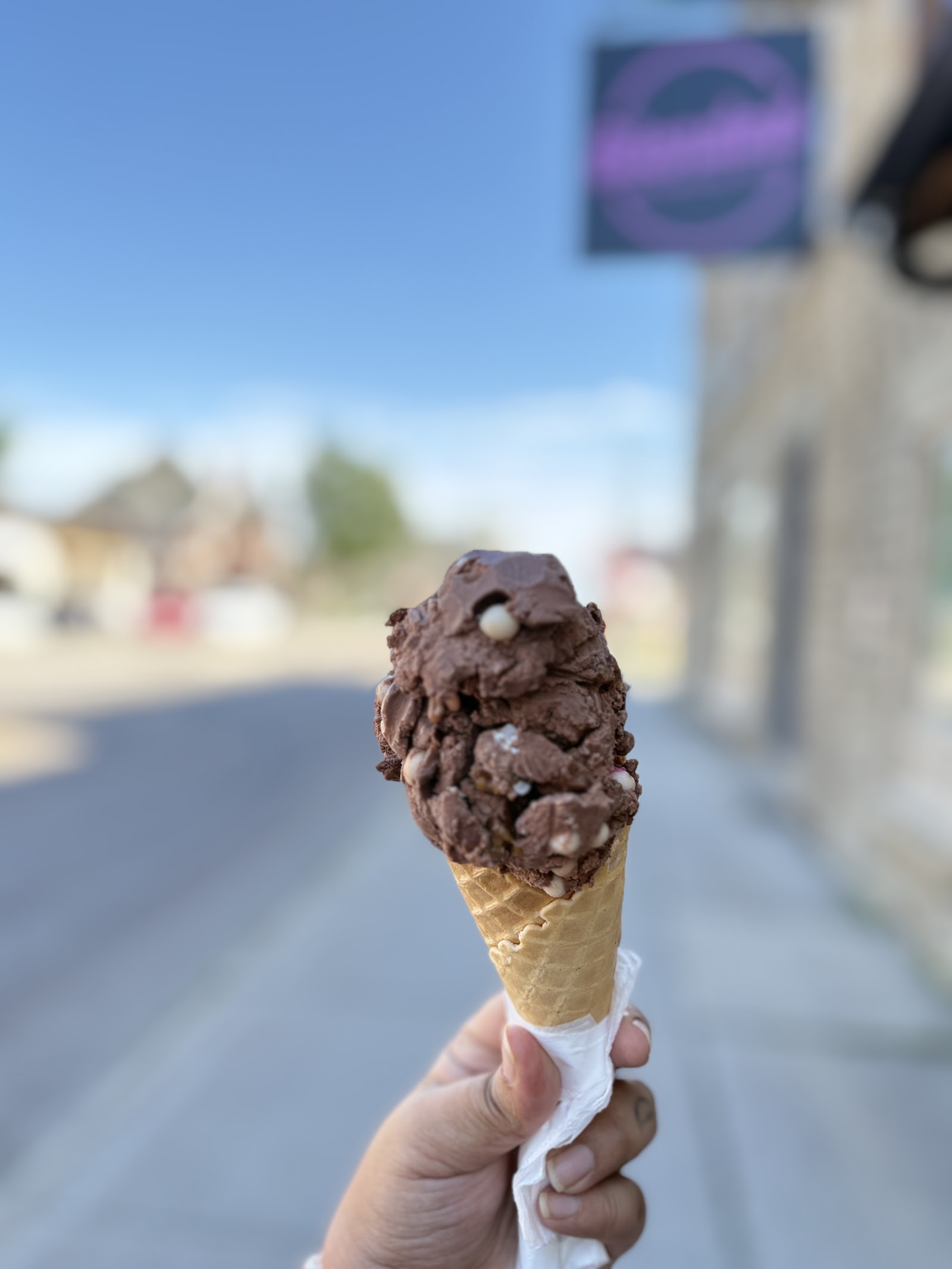 A chocolate ice cream cone held up outside the café