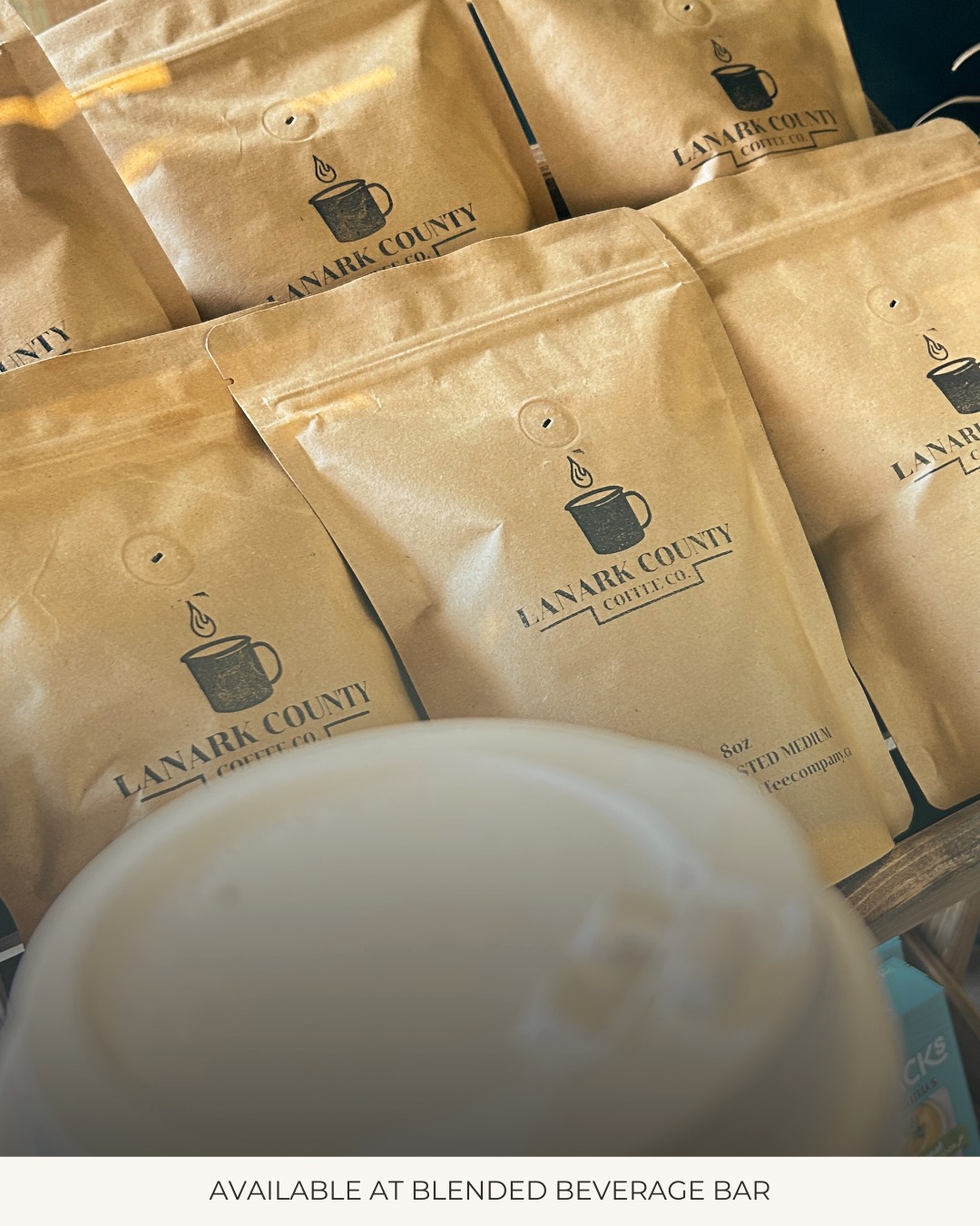 Bags of Lanark County Coffee Co. beans on the retail shelf beside a drink