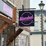 The Blended Beverage Bar hanging sign outside 230 Bridge Street in the snow — the café's own Instagram profile picture