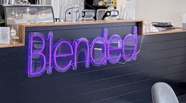 The purple neon "Blended" wordmark on the café counter