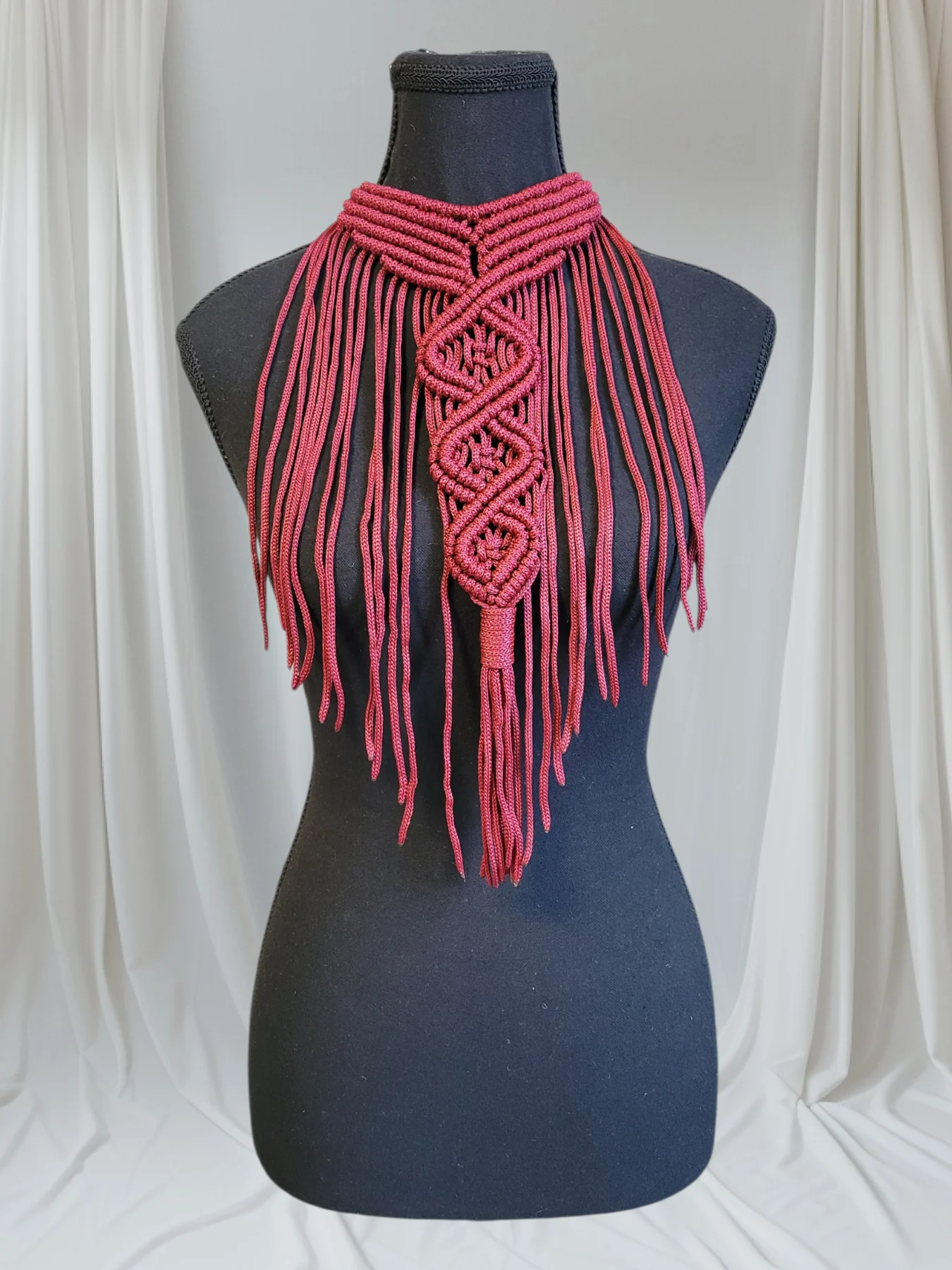 An author's macramé gorget in raspberry cord with long fringing, shown on a dress form