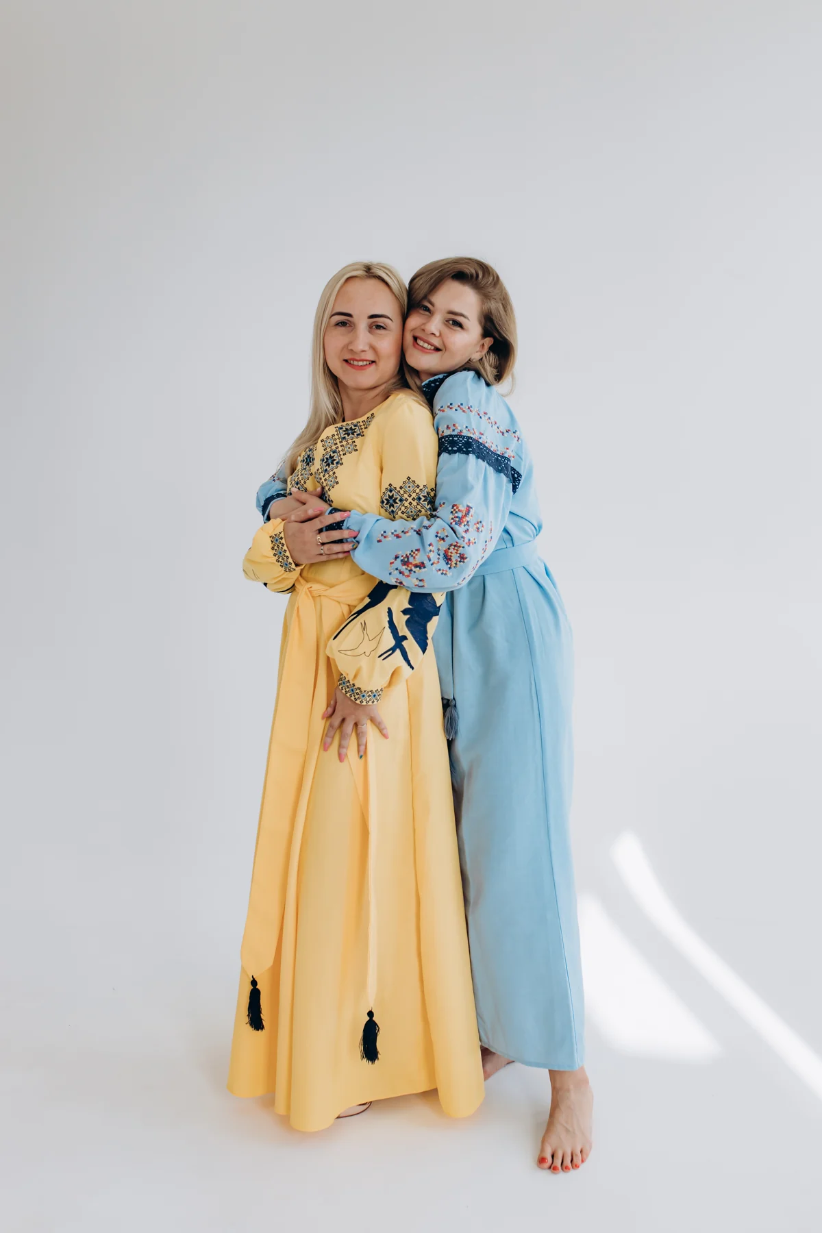 Two women in embroidered long dresses, one yellow and one pale blue, from ETNIKA UA's home page