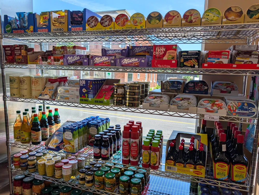 Shelves of Milka chocolate, Haribo, Finn Crisp and pumpernickel above the herring shelf, with Maggi seasoning and European sodas below.