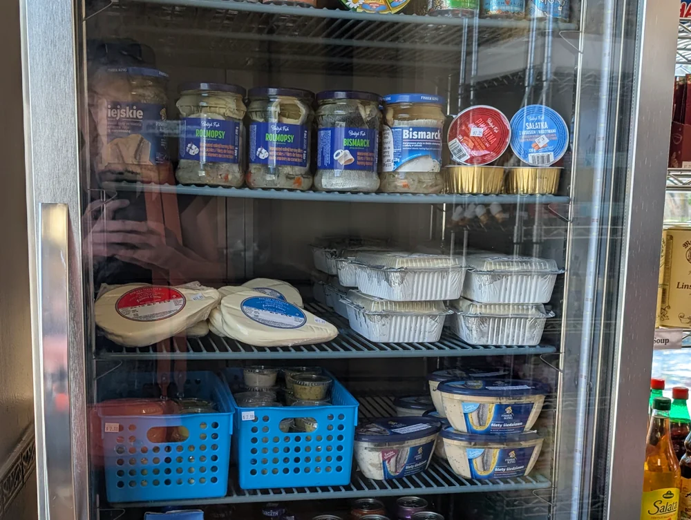 The cooler: jars of rolmops and Bismarck herring, cheeses and prepared salads on the shelves.