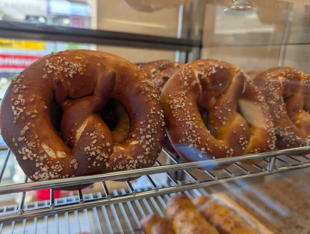 Classic soft pretzels with coarse salt on a wire rack in the bakery display case.
