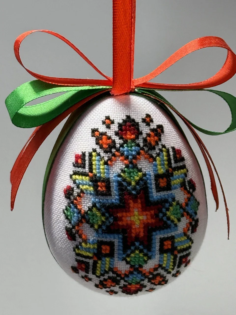 Hand-embroidered pysanka on a red-and-green ribbon
