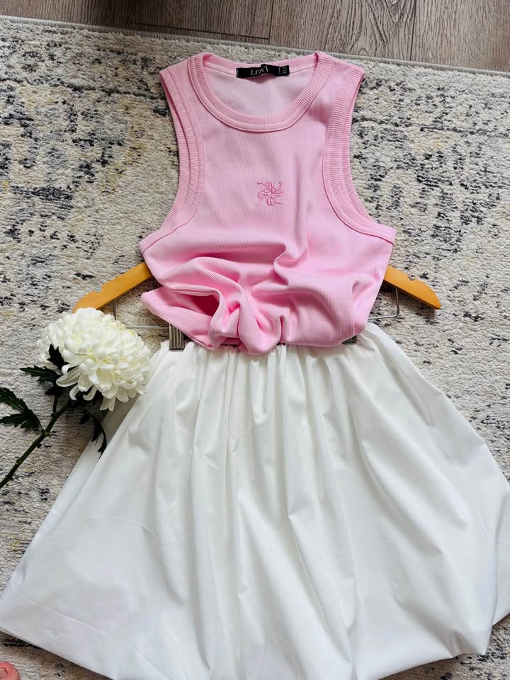 Pink ribbed top and white balloon skirt laid out on a hanger with a white chrysanthemum