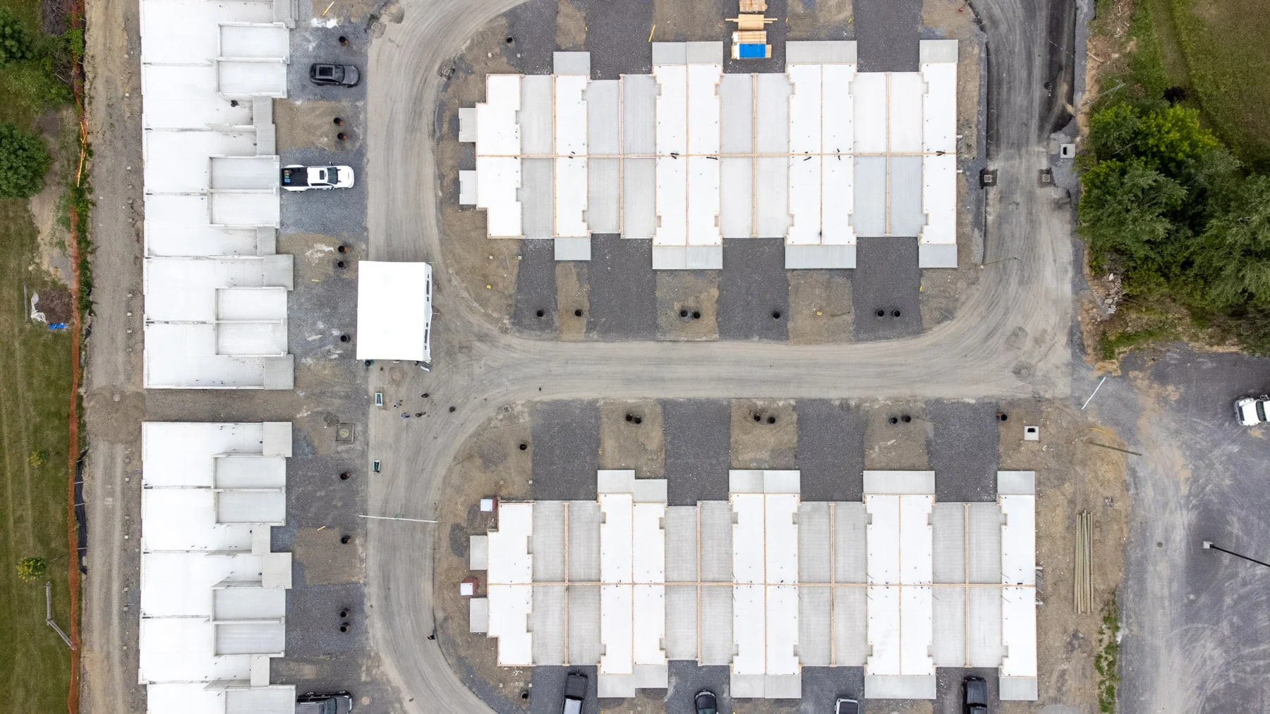 Overhead drone view of a townhouse subdivision under construction, poured foundations lining a new gravel street